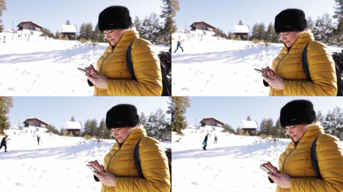 一名高加索妇女在她的寒假期间在山上使用手机