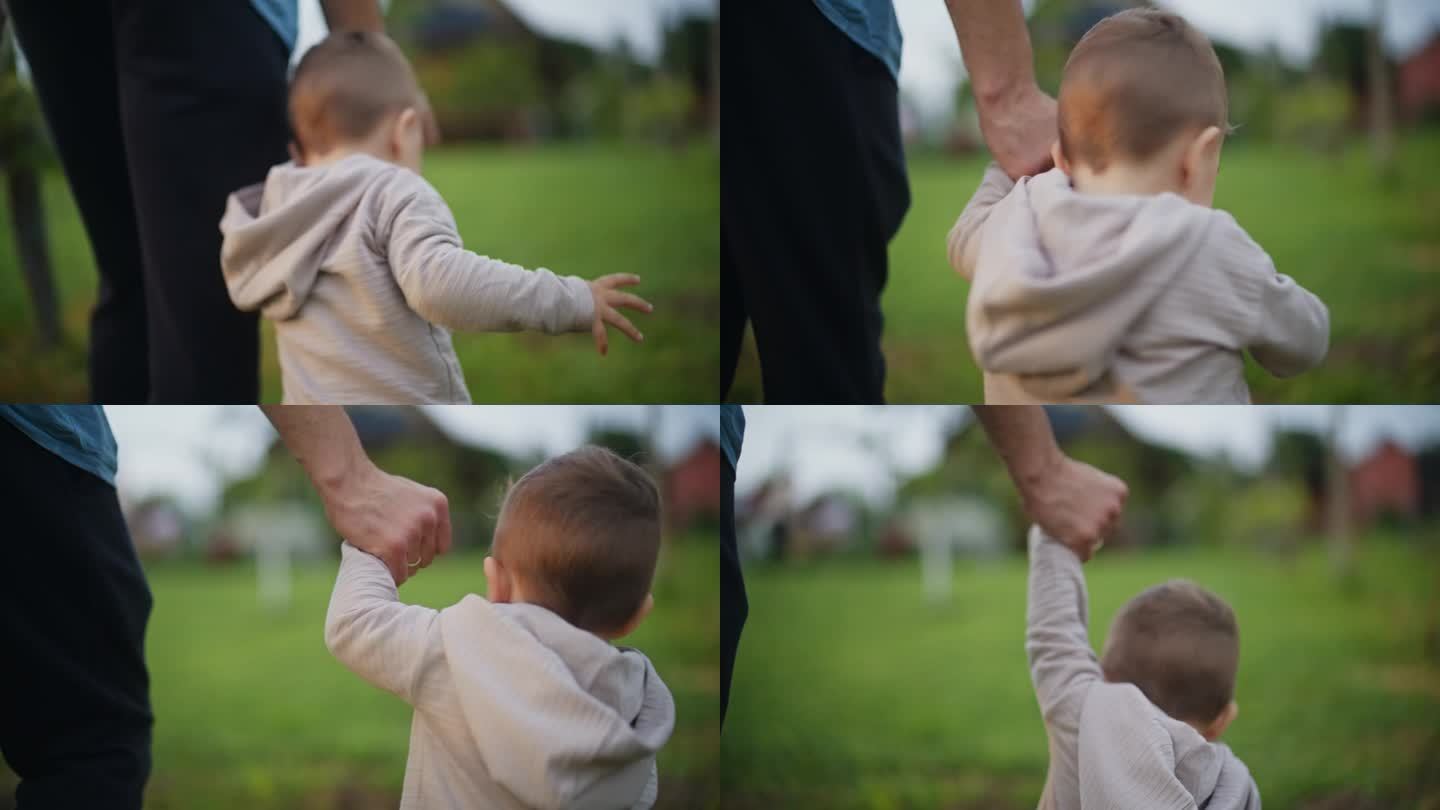 父亲牵着男婴的手走在户外。父与子