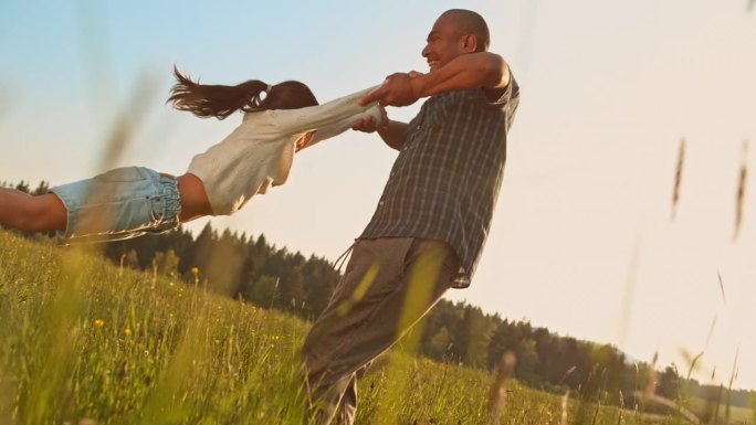父亲抱着女儿在草地上旋转