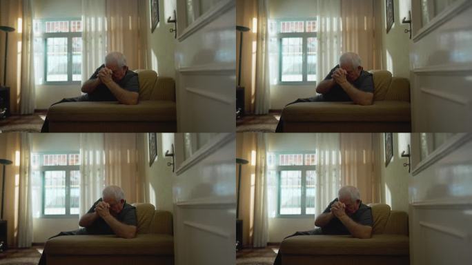 在家祈祷的老人，坐在沙发上紧握双手祈祷的忠实的老人，真诚坦率的老人，忠诚的白人男性