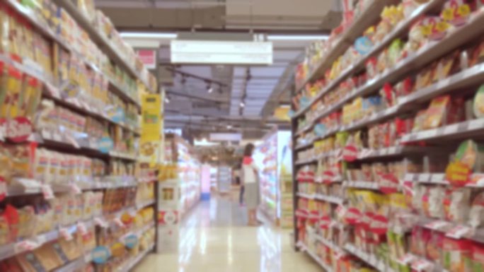在超市内，手推车在人群和货架间移动的模糊图像
