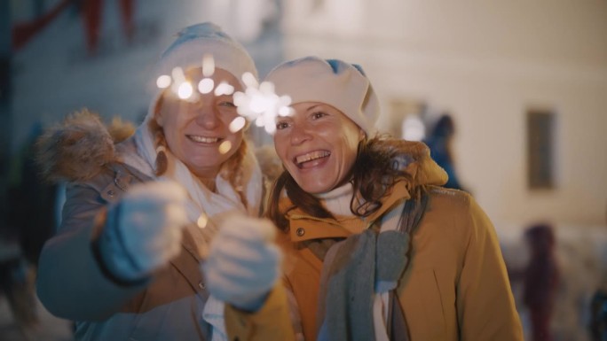 SLO - MO相机围绕圣诞市场上两个拿着烟花的女人旋转