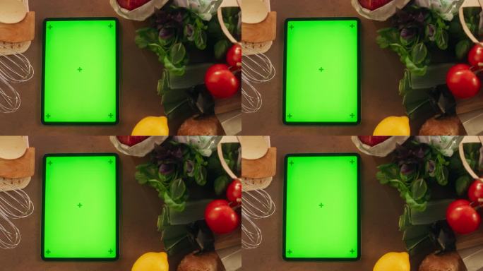 平板电脑的顶部静态视图与模拟绿屏显示。一个设备与蔬菜垂直放置在厨房桌子上的电影镜头。在线数字营销模板