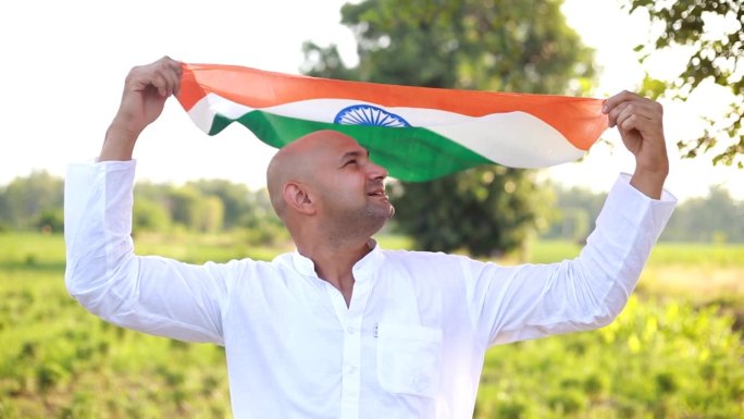人们在屋外的农田里挥舞着印度国旗