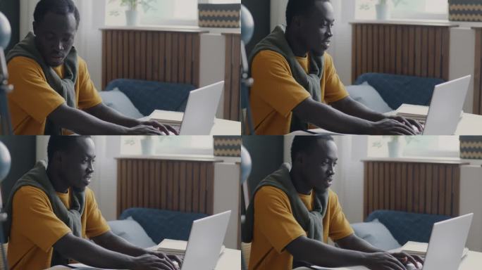 年轻的非裔美国学生，在家用笔记本电脑打字，忙着完成大学作业