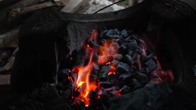 木柴在火中燃烧，木炭在炉子中燃烧。热炉子上燃烧的煤的特写。烧红的，滋滋作响的煤。