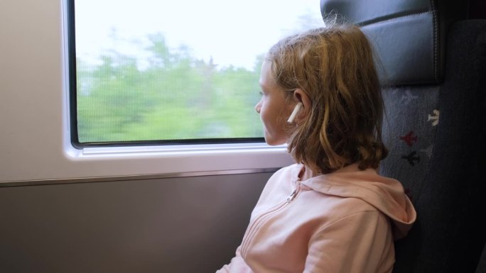 小女孩在火车上透过窗户往外看