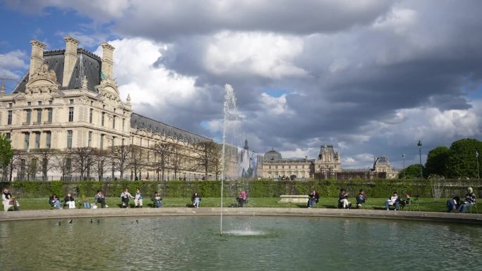 2023年5月3日，法国巴黎。阳光明媚的日子里，人们坐在杜伊勒里花园喷泉旁的长椅上放松。