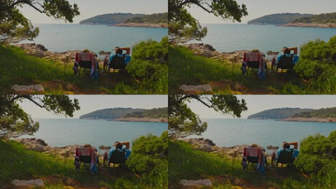 度假期间，一对夫妇坐在椅子上看着大海。