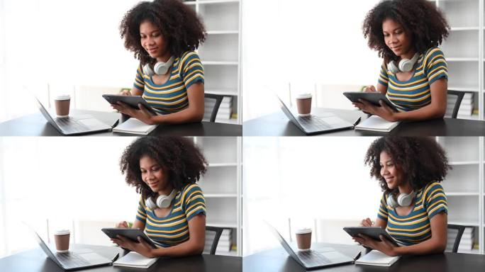 非洲女孩图书馆的女学生坐在书桌前用笔记本电脑和平板电脑搜索网上信息。