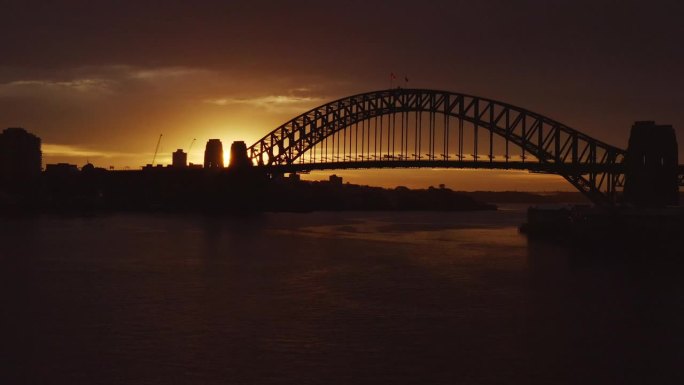 在金色的冬日日出中，广阔的背光映衬出悉尼海港大桥的剪影