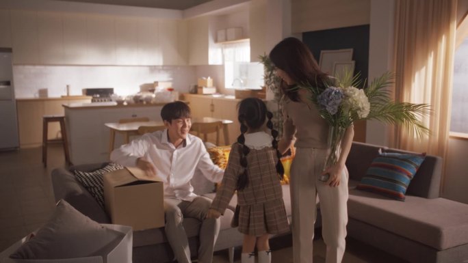 一个幸福的韩国家庭来到他们新买的房子:父母和他们可爱的女儿为新的开始感到兴奋，一起分享他们生活中的一