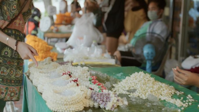兴高采烈的年轻游客询问美丽花环的价格。在曼谷的一家花店。