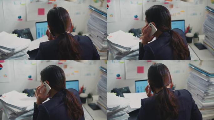 年轻的女企业家一边打电话一边在办公室里看文件。