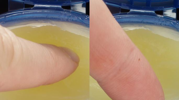 我从罐子里取了一点凡士林涂在手指上，拿到相机前，微距镜头。垂直视频。