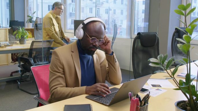 非裔美国经理戴着耳机在笔记本电脑上工作