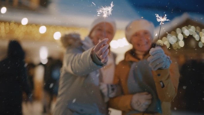 下雪的时候，妇女们在圣诞市场上欣赏炫目的烟花。圣诞集市上的欢乐时光。