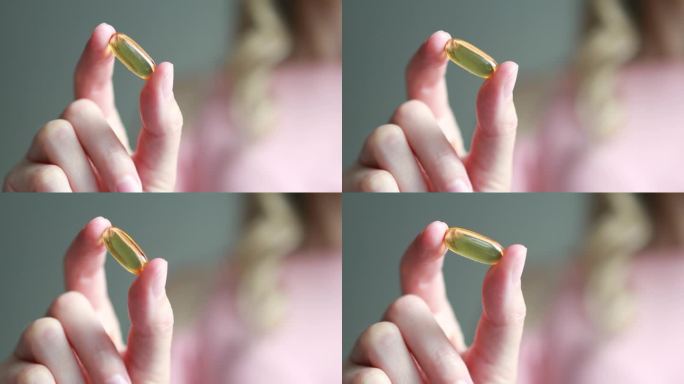一个女人手掌里的黄色omega-3营养补充品或鱼油或维生素D3胶囊的特写