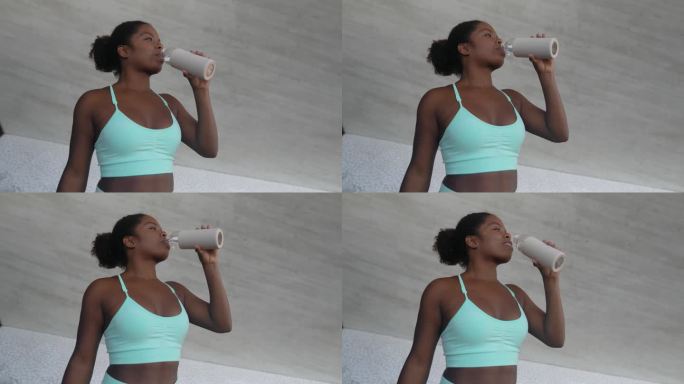 年轻的非洲妇女在户外锻炼时休息喝水-运动人的生活方式概念