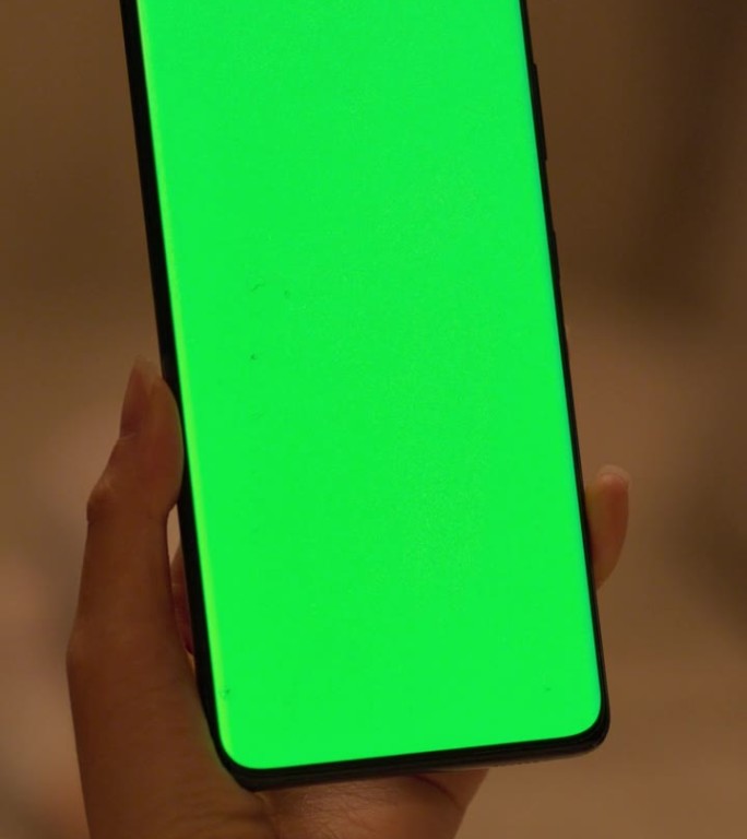 垂直屏幕:匿名年轻女性使用绿色屏幕模拟显示的智能手机。在舒适的现代家庭环境中浏览互联网，查看社交媒体