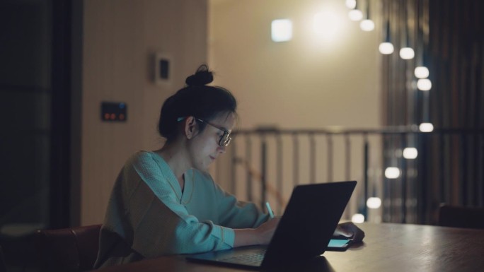 亚洲女商人使用笔记本电脑和平板电脑进行在线学习和夜间工作。