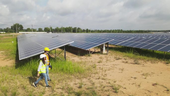 无人机拍摄的两名太阳能工程师在太阳能农场工作。