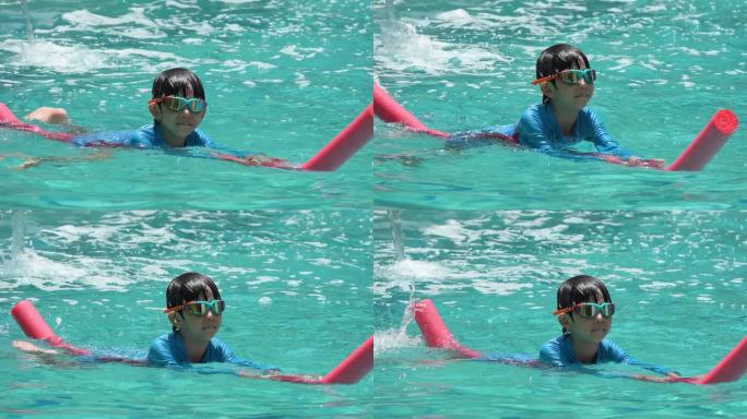 一个男孩戴着泳镜漂浮在泳池上，慢镜头