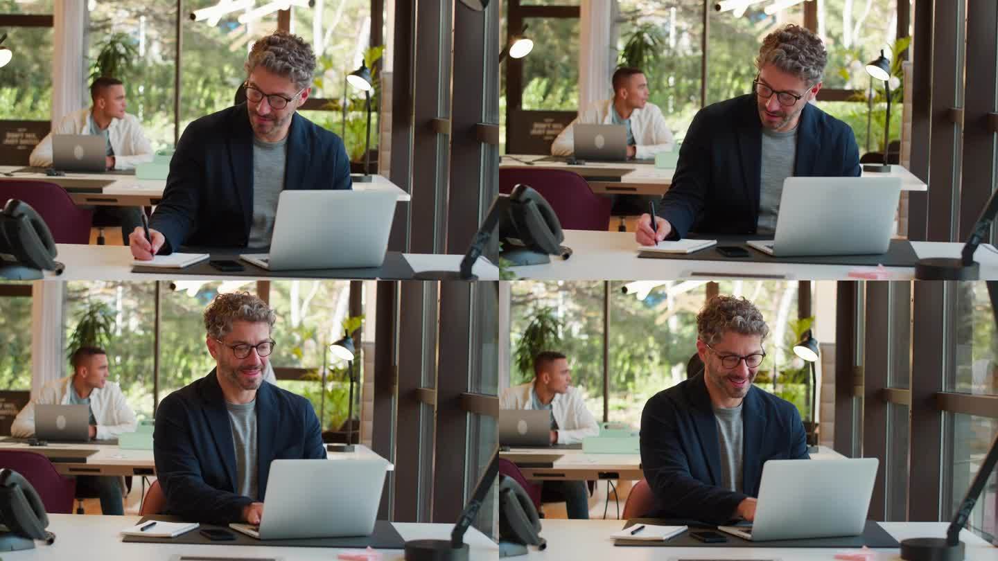 成熟的商人戴着眼镜在办公室工作，在笔记本上写字
