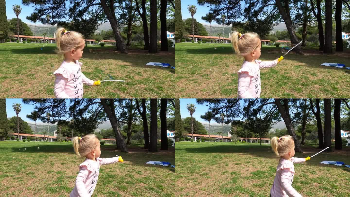 小女孩挥舞着玩具套索，在草坪上吹肥皂泡