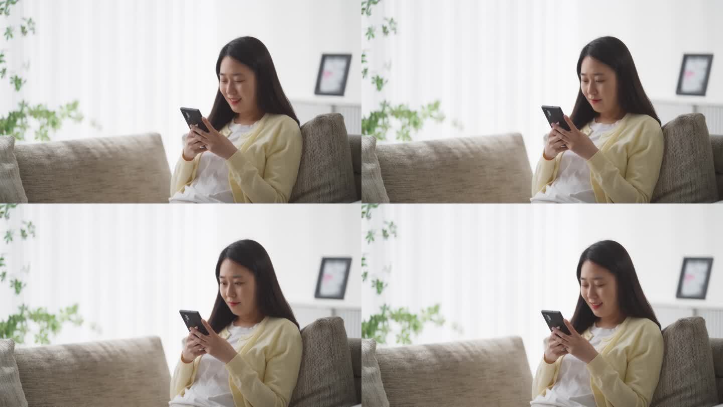 年轻的韩国女性沉迷于网络，用智能手机享受休闲时光，在沙发上休息，探索社交媒体和娱乐应用程序
