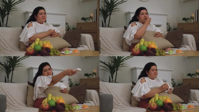 亚洲肥胖女性一边看电视剧，一边吃，不健康的生活理念。