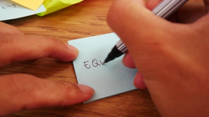 男子用黑笔和柔焦场景在蓝色纸上写股票笔记。
