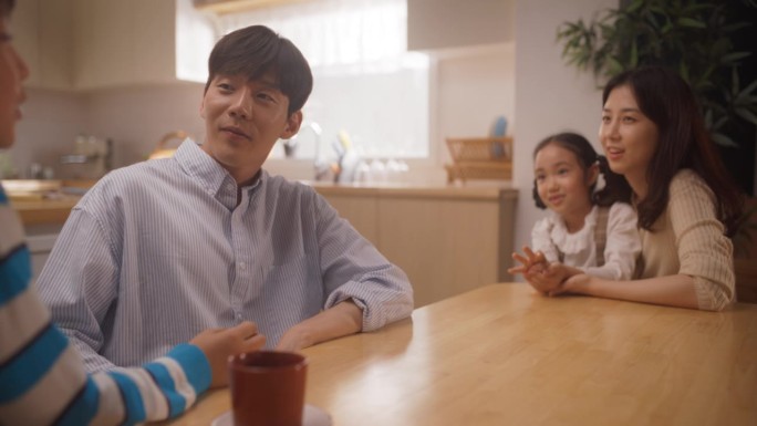 幸福的韩国小家庭在阳光明媚的家里聊天的肖像。父母与孩子沟通，对他们充满深情，认可并倾听他们。家庭讨论