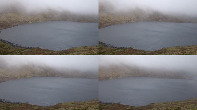 在爱尔兰刮大风的一天，一个宁静的高原湖泊的表面点缀着低空飞舞的云，描绘了一幅迷人的画面。