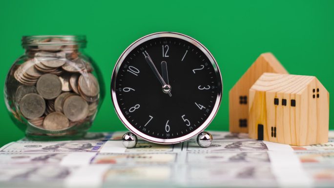 钟，钱和房子。工作时间，时间流逝时间。模型木屋。硬币放在玻璃罐里。