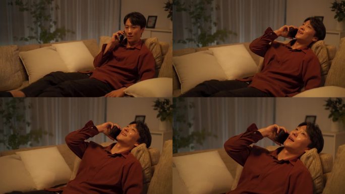 一名年轻的韩国男子通过手机获得了积极的消息。快乐的亚洲男性在与朋友通话时微笑。睡觉前躺在家里沙发上的