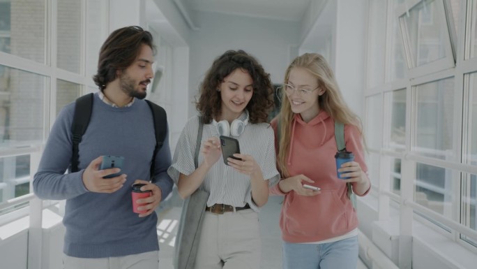 快乐的年轻人走在大学走廊上，用智能手机讨论社交媒体内容的慢镜头