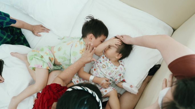 一个亚洲家庭在医学检查室等待孩子的儿科医生时给她的儿子们玩耍。健康的生活方式。甲型流感病毒。