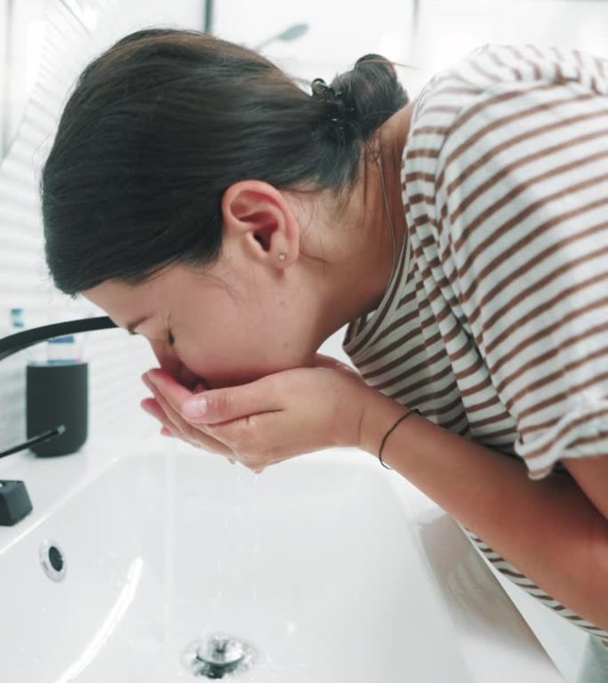 一名妇女在浴室用水洗脸。