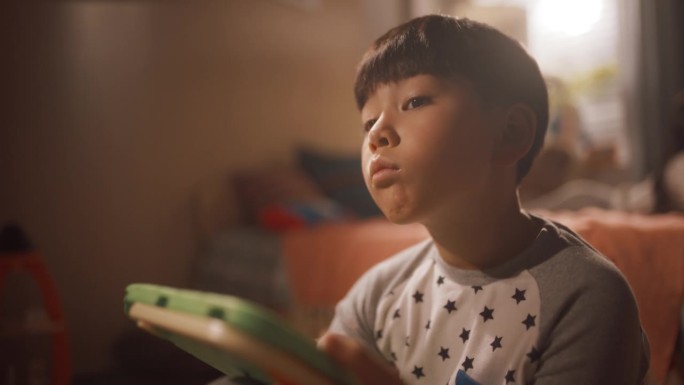 体贴的亚洲男孩在孩子的卧室里用平板电脑学习。可爱的天才韩国孩子思考，解决问题的数字练习上的设备