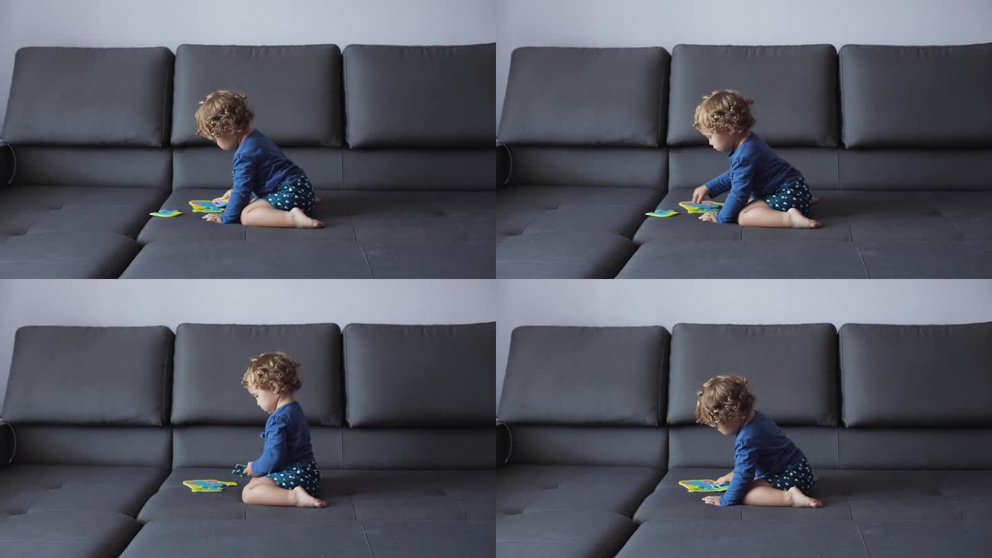 一个浅卷发的小女孩正坐在家里的沙发上，玩着学解大象图片的彩色拼图。