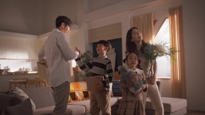幸福的韩国小家庭为他们的新家感到兴奋:年轻的父母和他们活跃的孩子庆祝搬进来，享受他们买的宽敞的新公寓