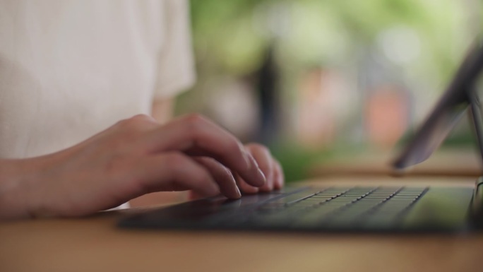 女人的手使用笔记本电脑和键盘打字