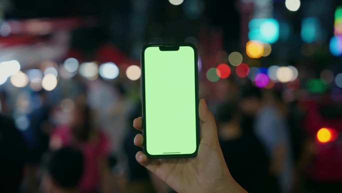 一名女子手持绿屏智能手机，在瑶华路步行街