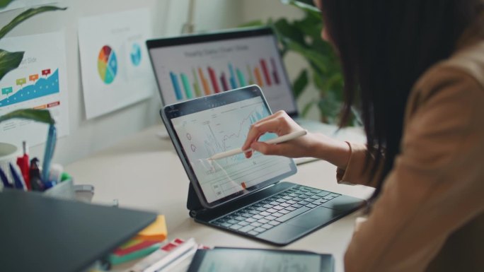 女商人使用数字平板电脑分析商业数据财务分析师在笔记本电脑上看图表