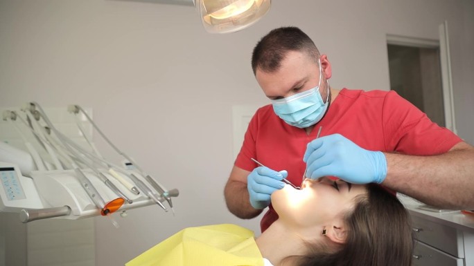 牙医用口腔镜和牙科挖掘机检查病人的牙齿。
