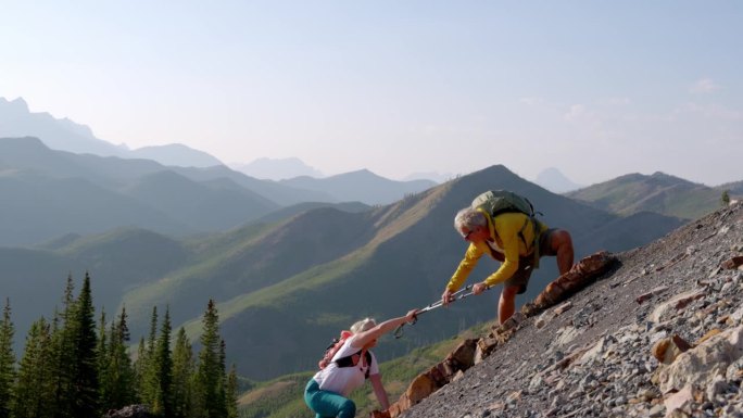 登山运动员向挣扎上坡的同伴伸出援助之手