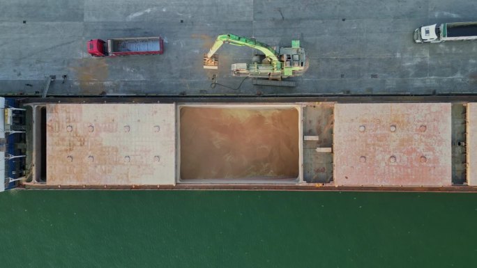 在港口仓库使用门式起重机进行装货作业。粮食从货船转运到卡车货舱