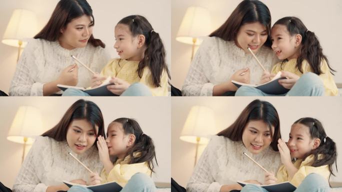 亚洲母亲在家教女儿做作业，在床上玩耍。年轻的母亲在家照顾女儿并教她画画。