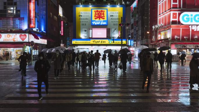 日本人在秋叶原东京使用雨伞行走过马路、骑自行车、通勤交通等夜间交通工具。都市生活、娱乐区、亚洲旅游或